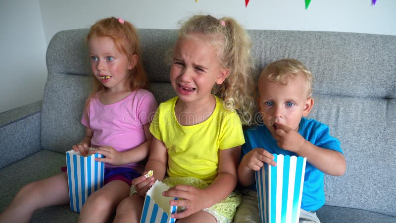 Bambini che mangiano popcorn e piangono Bambini tristi che guardano film teatrali sul cinema domestico