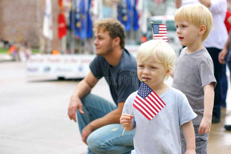 Bambini che tengono le bandiere americane all'evento di parata di Patriotics immagine stock Bambini che tengono le bandiere americane all'evento di parata di Patriotics immagine stock