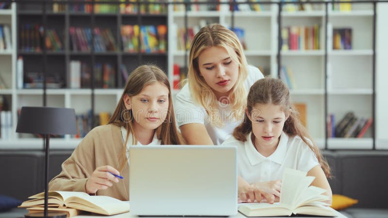 Bambini che usano un computer portatile per fare un lavoro e gli insegnanti per aiutarli