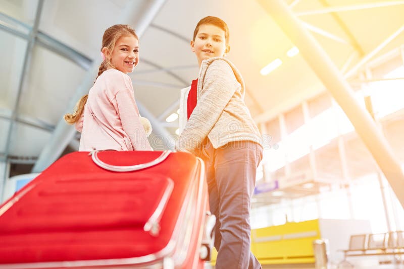 Bambini con le valigie all'aeroporto prima della partenza immagine stock libera da diritti Bambini con le valigie all'aeroporto prima della partenza immagine stock libera da diritti