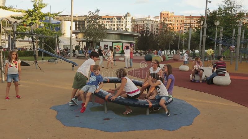 Bambini dell'età differente che giocano sulla rotonda del campo da giuoco, sorridere felice dei bambini