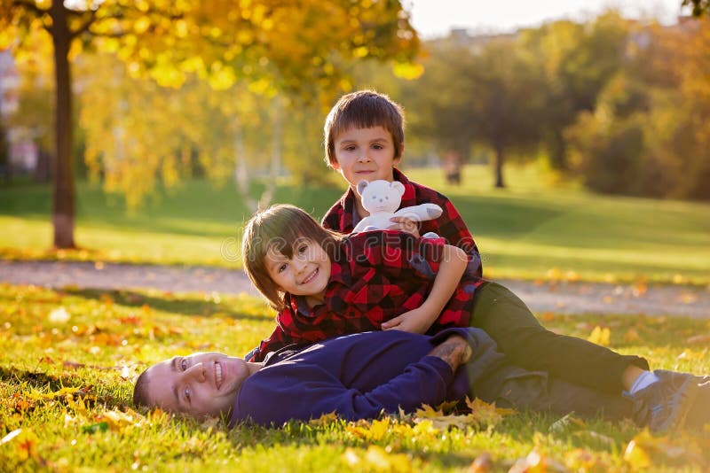 Bambini divertenti svegli, giocanti con il loro padre nel parco, autu immagini stock Bambini divertenti svegli, giocanti con il loro padre nel parco, autu immagini stock