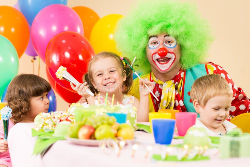Bambini felici che celebrano la festa di compleanno con il pagliaccio immagine stock libera da diritti Bambini felici che celebrano la festa di compleanno con il pagliaccio immagine stock libera da diritti
