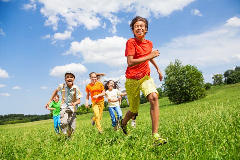 Bambini felici che corrono insieme nel campo immagine stock Bambini felici che corrono insieme nel campo immagine stock