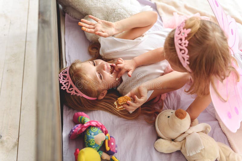 Bambini felici che giocano con l'alimento dolce in camera da letto fotografia stock libera da diritti Bambini felici che giocano con l'alimento dolce in camera da letto fotografia stock libera da diritti