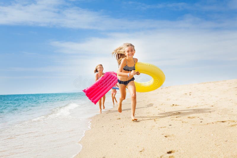 Bambini felici che hanno una corsa sulla spiaggia soleggiata nell'estate immagine stock libera da diritti Bambini felici che hanno una corsa sulla spiaggia soleggiata nell'estate immagine stock libera da diritti
