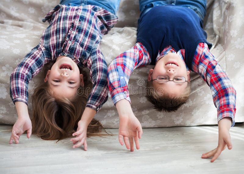 Bambini felici sottosopra sul sofà fotografie stock libere da diritti Bambini felici sottosopra sul sofà fotografie stock libere da diritti