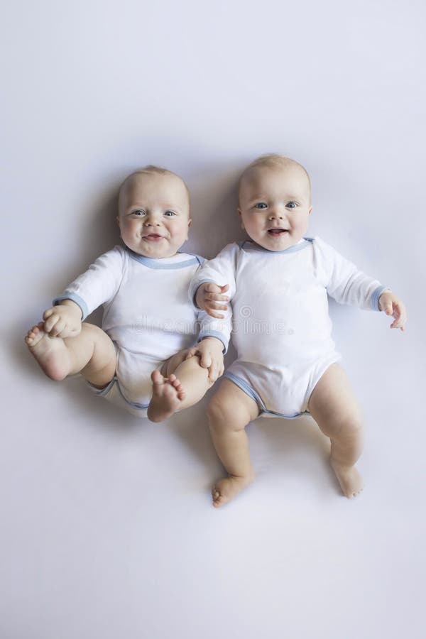 Bambini gemellati grassottelli di risata nel bianco immagine stock Bambini gemellati grassottelli di risata nel bianco immagine stock
