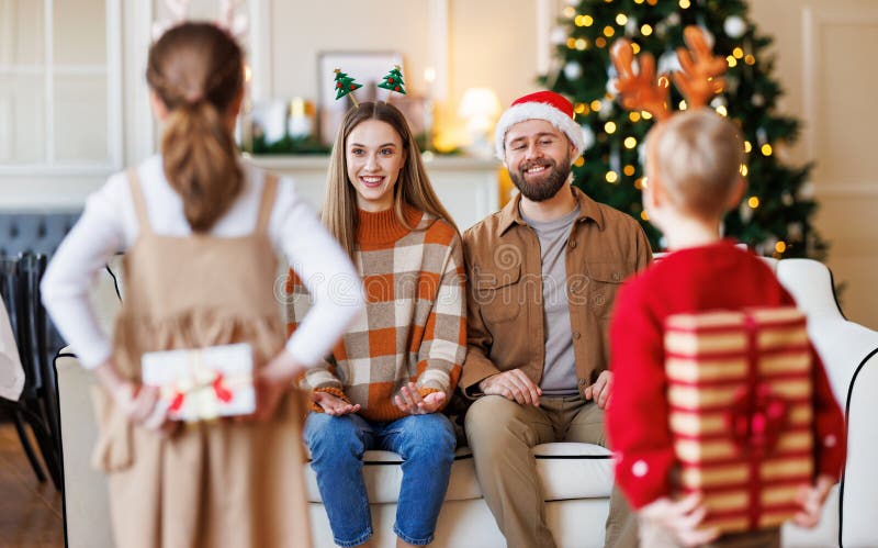 Bambini piccoli con scatole da regalo confezionate dietro le quinte, sorprendono i genitori la mattina di natale immagini stock