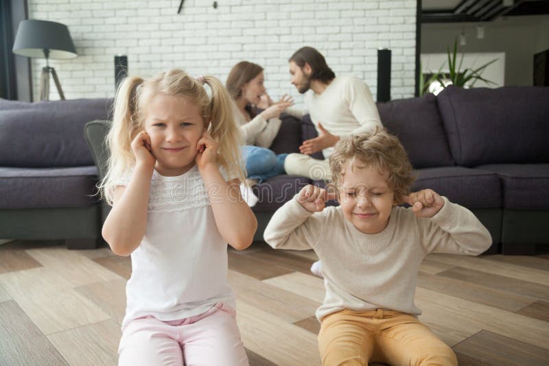 Little children boy and girl put fingers in ears not to hear parents arguing at background, son and daughter tired of family conflicts, parental arguments impact on children, divorce and kids concept. Little children boy and girl put fingers in ears not to hear parents arguing at background, son and daughter tired of family conflicts, parental arguments impact on children, divorce and kids concept