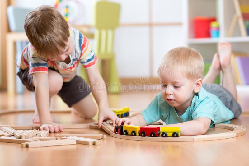 Bambini svegli che giocano con il treno di legno Il bambino scherza il gioco con i blocchi ed i treni Ragazzi che costruiscono la fotografie stock Bambini svegli che giocano con il treno di legno Il bambino scherza il gioco con i blocchi ed i treni Ragazzi che costruiscono la fotografie stock