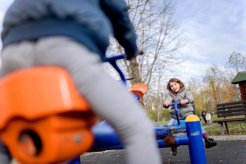 Bambini svegli divertendosi sul movimento alternato al campo da giuoco fotografia stock libera da diritti Bambini svegli divertendosi sul movimento alternato al campo da giuoco fotografia stock libera da diritti