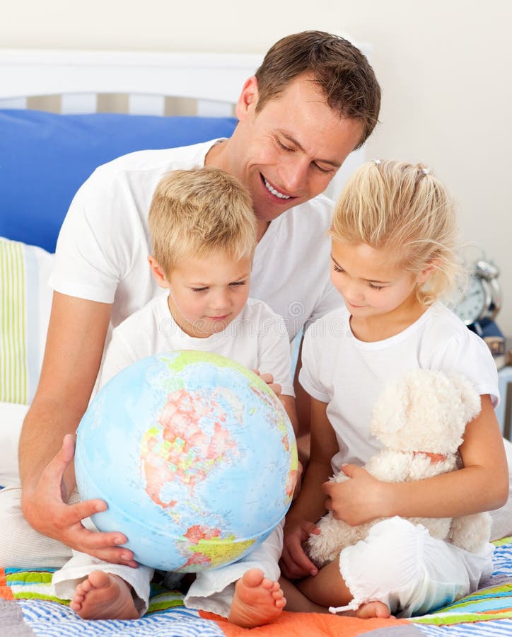 Bambini svegli e loro il padre che esaminano un glob fotografie stock Bambini svegli e loro il padre che esaminano un glob fotografie stock