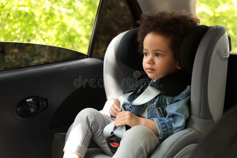 Bambino afroamericano sveglio che si siede nel sedile di sicurezza dentro l'automobile fotografia stock libera da diritti Bambino afroamericano sveglio che si siede nel sedile di sicurezza dentro l'automobile fotografia stock libera da diritti