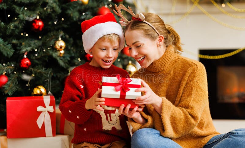 Bambino carino e madre sorridente che apre insieme i regali di natale