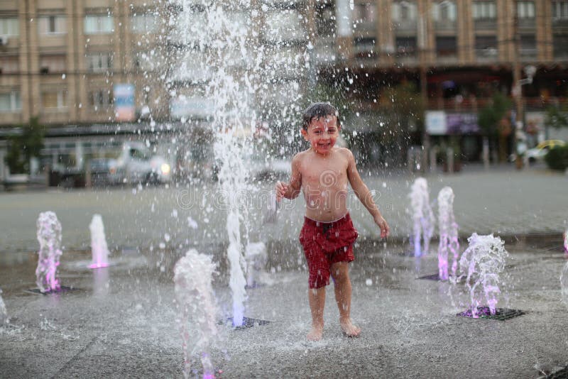 Bambino che cammina in una fontana di spruzzatura fotografia stock libera da diritti Bambino che cammina in una fontana di spruzzatura fotografia stock libera da diritti