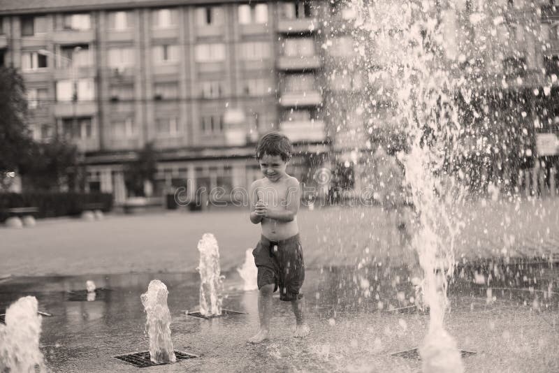 Bambino che cammina in una fontana di spruzzatura fotografia stock Bambino che cammina in una fontana di spruzzatura fotografia stock