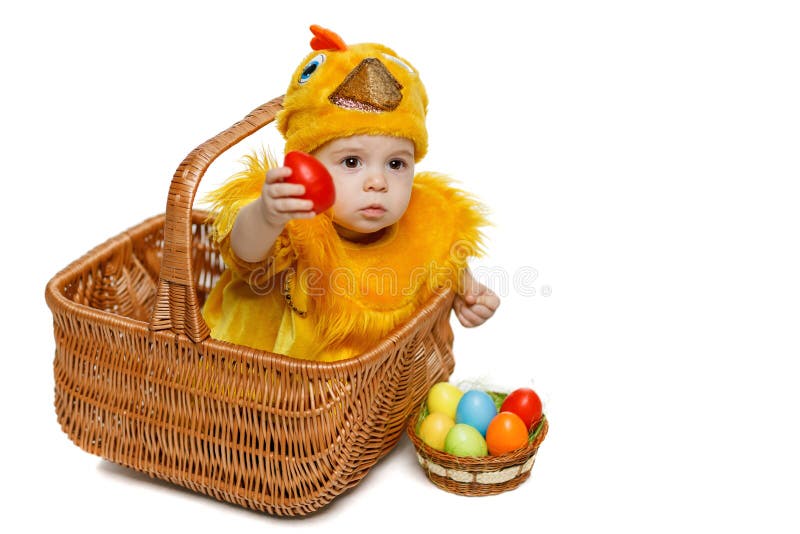 Bambino che si siede nel canestro di Pasqua in costume del pollo con le uova di Pasqua immagini stock Bambino che si siede nel canestro di Pasqua in costume del pollo con le uova di Pasqua immagini stock