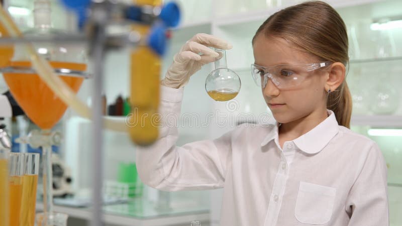 Bambino che studia chimica nel laboratorio della scuola, studente Girl Making Experiments fotografia stock Bambino che studia chimica nel laboratorio della scuola, studente Girl Making Experiments fotografia stock