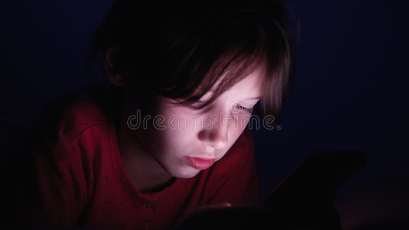 Bambino che utilizza smartphone nel buio