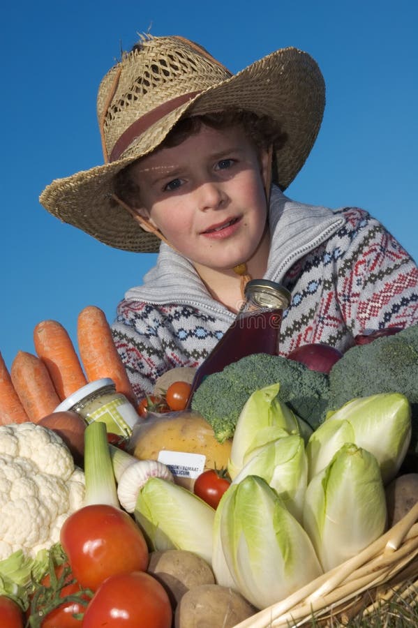 Boy (7) dressed as a farmer, with a large basket with vegetables against a clear blue sky. Boy (7) dressed as a farmer, with a large basket with vegetables against a clear blue sky