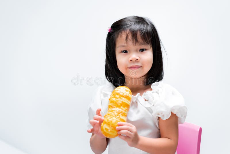 Bambino con un sorriso dolce che tiene in mano un pane lungo giallo. su fondo bianco fotografia stock