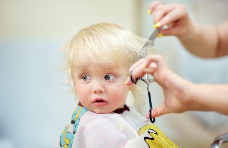Bambino del bambino che ottiene il suo primo taglio di capelli immagine stock Bambino del bambino che ottiene il suo primo taglio di capelli immagine stock