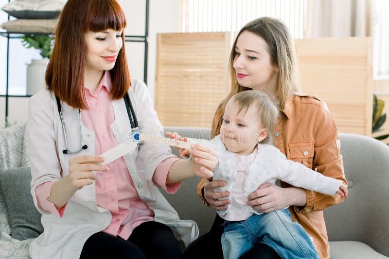 Bambino del bambino e della madre al ricevimento al pediatra del bambino Gola d'esame del pediatra femminile di piccolo malato immagine stock libera da diritti Bambino del bambino e della madre al ricevimento al pediatra del bambino Gola d'esame del pediatra femminile di piccolo malato immagine stock libera da diritti