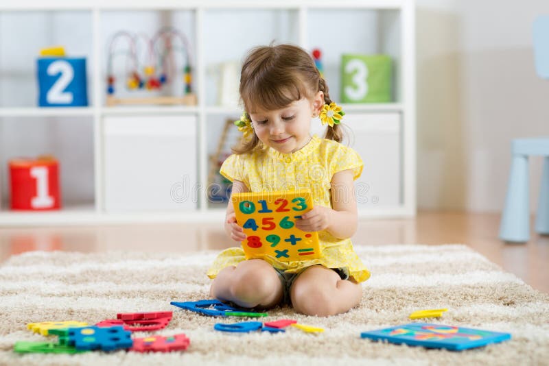 Bambino della bambina che gioca con i lotti delle cifre di plastica variopinte o dei numeri all'interno fotografia stock libera da diritti Bambino della bambina che gioca con i lotti delle cifre di plastica variopinte o dei numeri all'interno fotografia stock libera da diritti