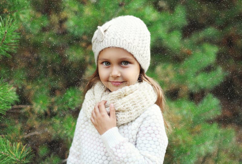 Bambino della bambina che porta cappello e maglione tricottati con la sciarpa vicino all'albero di Natale immagine stock libera da diritti Bambino della bambina che porta cappello e maglione tricottati con la sciarpa vicino all'albero di Natale immagine stock libera da diritti