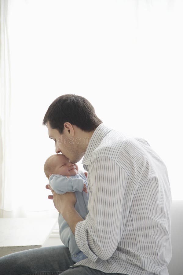 Bambino di Kissing His Newborn del padre fotografia stock Bambino di Kissing His Newborn del padre fotografia stock