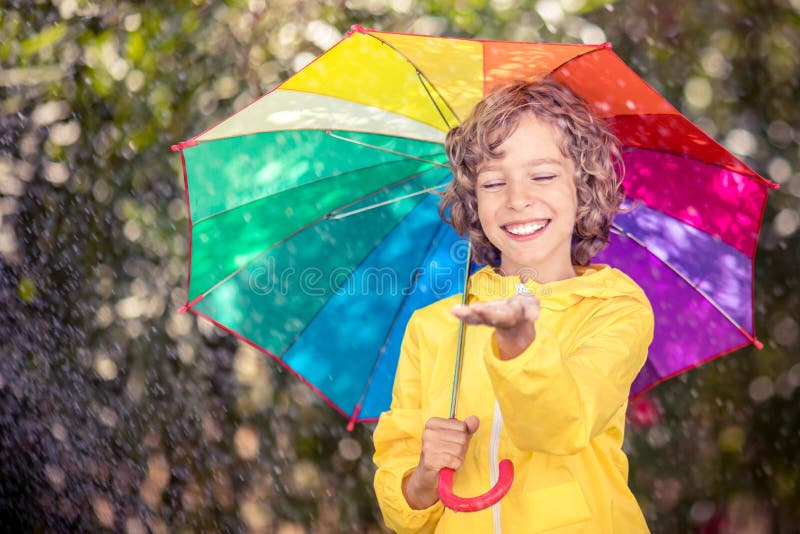 Bambino felice che gioca nella pioggia fotografie stock Bambino felice che gioca nella pioggia fotografie stock