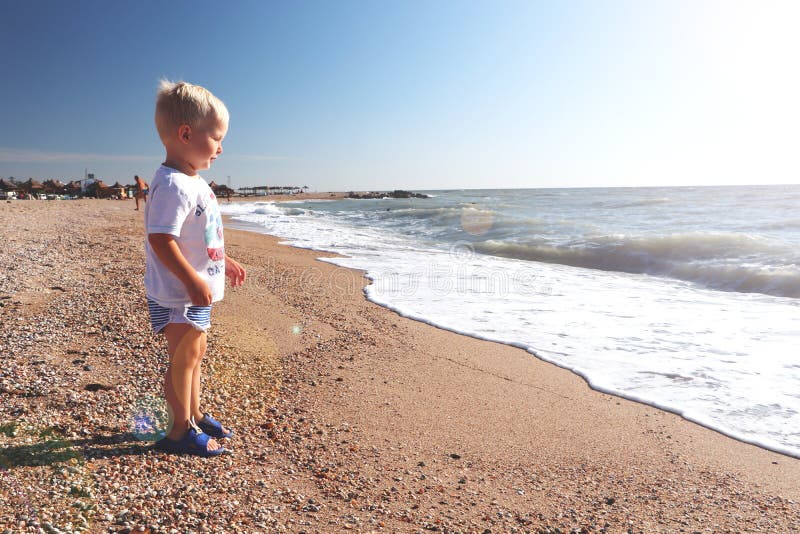 Bambino felice che gioca sulla spiaggia fotografia stock Bambino felice che gioca sulla spiaggia fotografia stock