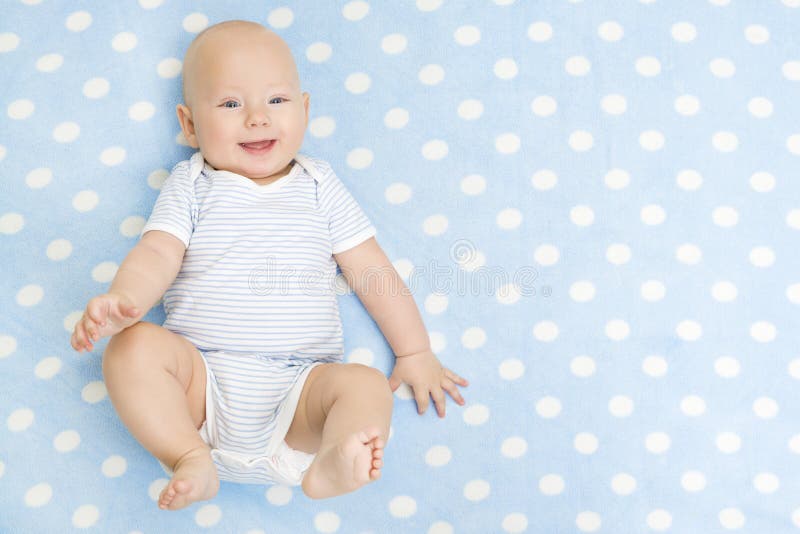 Bambino felice che si trova sul fondo blu del tappeto, bambino infantile sorridente fotografia stock