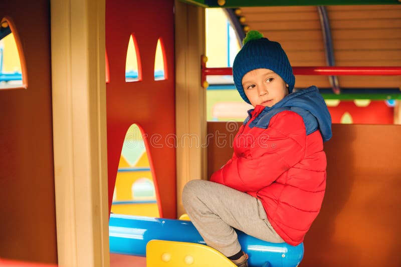 Bambino felice sul campo da giuoco variopinto del castello Ragazzino sveglio che gioca all'aperto nel tempo freddo di autunno Inf immagine stock