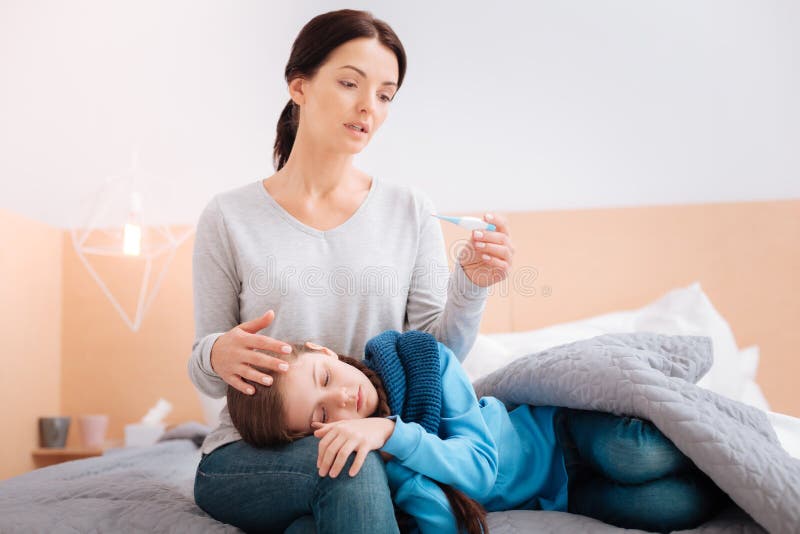 Bambino malato sulle ginocchia di una madre preoccupata immagine stock Bambino malato sulle ginocchia di una madre preoccupata immagine stock