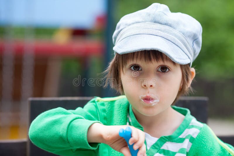 Bambino piccolo sorridente sveglio che mangia yogurt immagini stock Bambino piccolo sorridente sveglio che mangia yogurt immagini stock