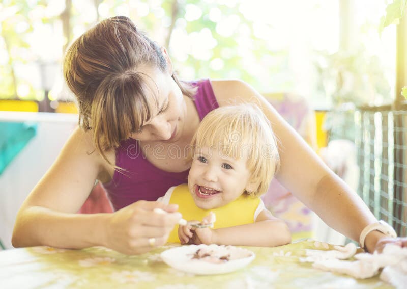 Bambino piccolo sveglio dell'alimentazione della mamma immagine stock Bambino piccolo sveglio dell'alimentazione della mamma immagine stock