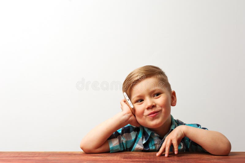 Bambino sorridente divertente che gioca con lo smartphone fotografia stock Bambino sorridente divertente che gioca con lo smartphone fotografia stock