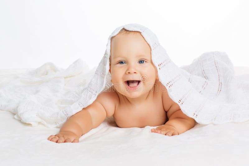 Bambino sorridente sveglio che si trova sull'asciugamano isolato su bianco immagini stock Bambino sorridente sveglio che si trova sull'asciugamano isolato su bianco immagini stock