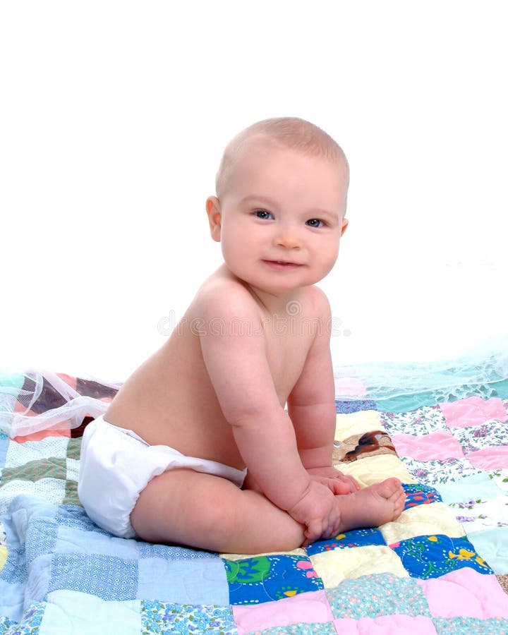 Baby boy sitting in front of white background on a multicolored quilt. Baby boy sitting in front of white background on a multicolored quilt