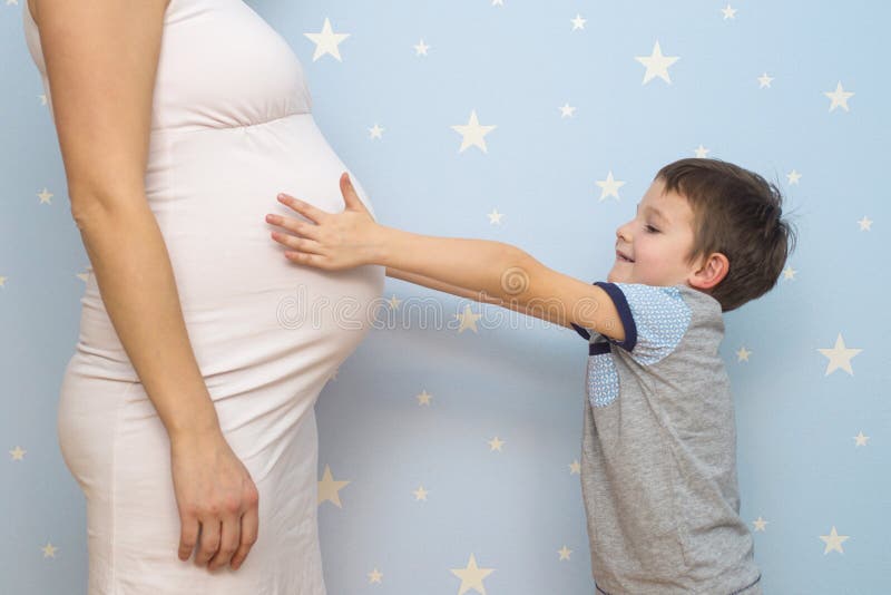 Bambino sveglio che abbraccia la madre incinta della pancia Bambino felice che abbraccia la pancia della madre incinta Gravidanza fotografia stock Bambino sveglio che abbraccia la madre incinta della pancia Bambino felice che abbraccia la pancia della madre incinta Gravidanza fotografia stock