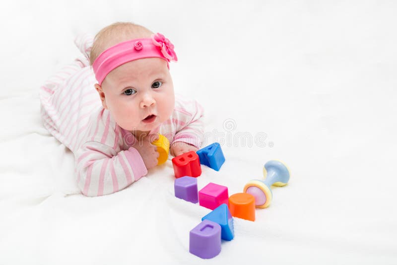 Bambino sveglio che gioca con il giocattolo variopinto Bambino neonato, bambina che esamina la macchina fotografica e strisciare fotografie stock Bambino sveglio che gioca con il giocattolo variopinto Bambino neonato, bambina che esamina la macchina fotografica e strisciare fotografie stock