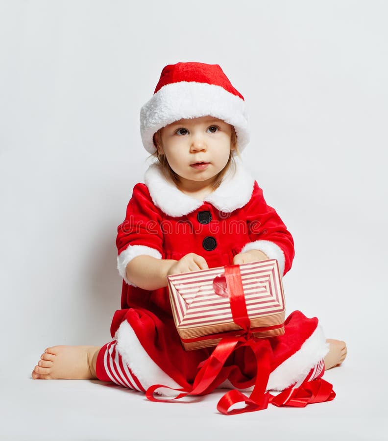 Bambino sveglio in contenitore di regalo d'apertura di Natale del cappello di Santa fotografie stock Bambino sveglio in contenitore di regalo d'apertura di Natale del cappello di Santa fotografie stock
