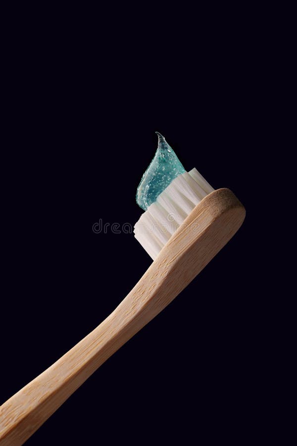 Bamboo-tandpensel med genomskinlig blå tandkräm på en mörkblå bakgrund. royaltyfri bild