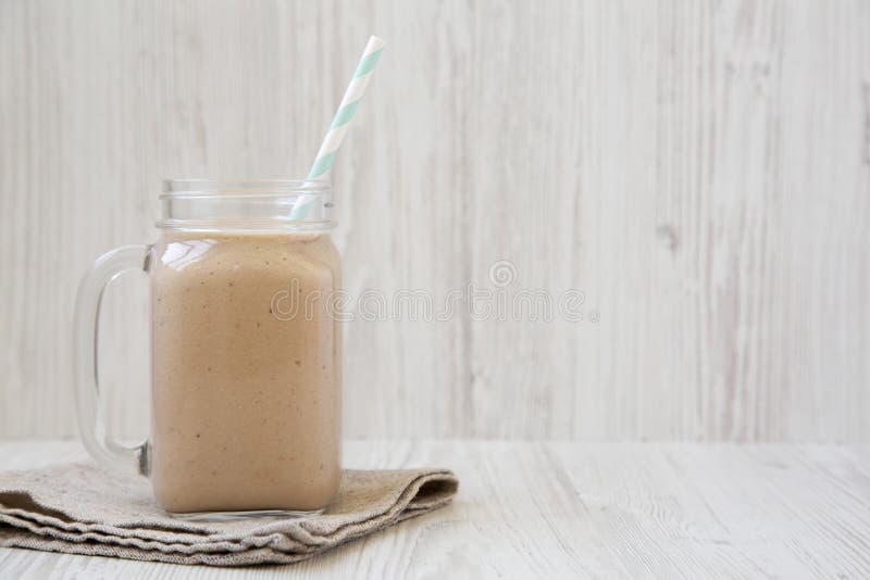 Banana apple smoothie in a glass jar mug, side view. Copy space
