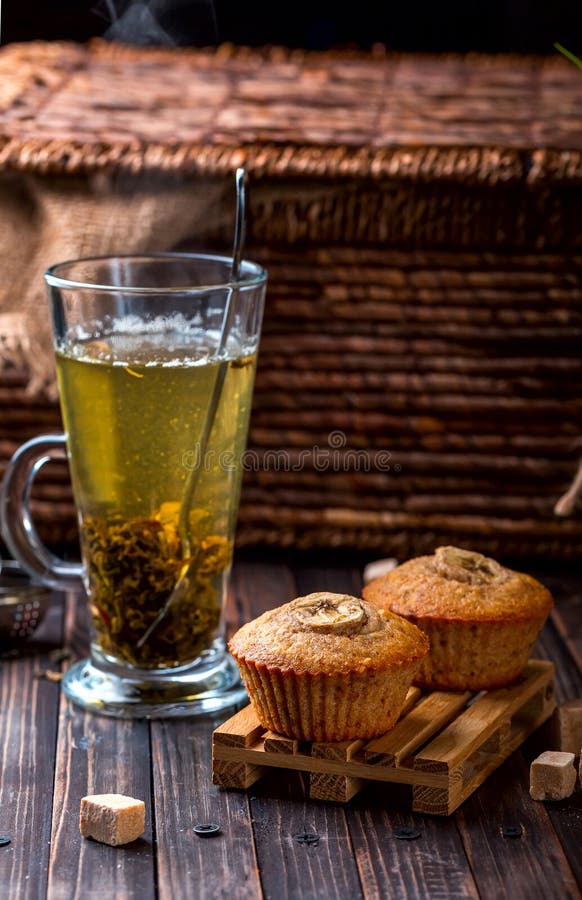 Banana cupcake on a wooden stand. Transparent Cup with green tea royalty free stock image Banana cupcake on a wooden stand. Transparent Cup with green tea royalty free stock image