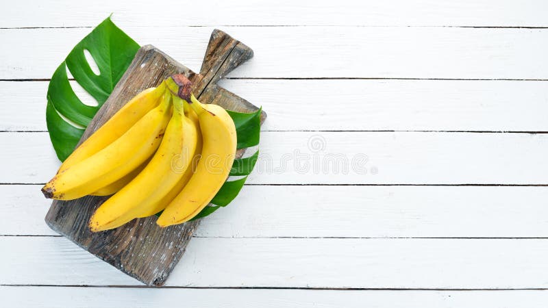 Banana with green leaves on a white wooden table. Tropical Fruits. Top view.