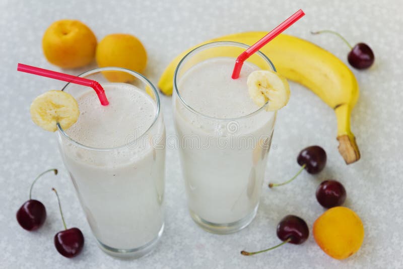 Banana smoothie with milk, cherry, peaches and banana on a white table