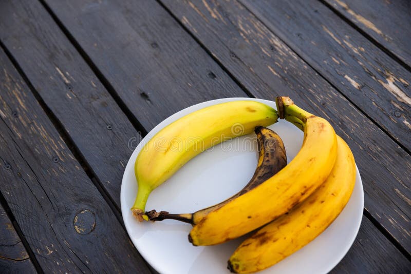 Banane în diferite stări de maturare pe o placă.